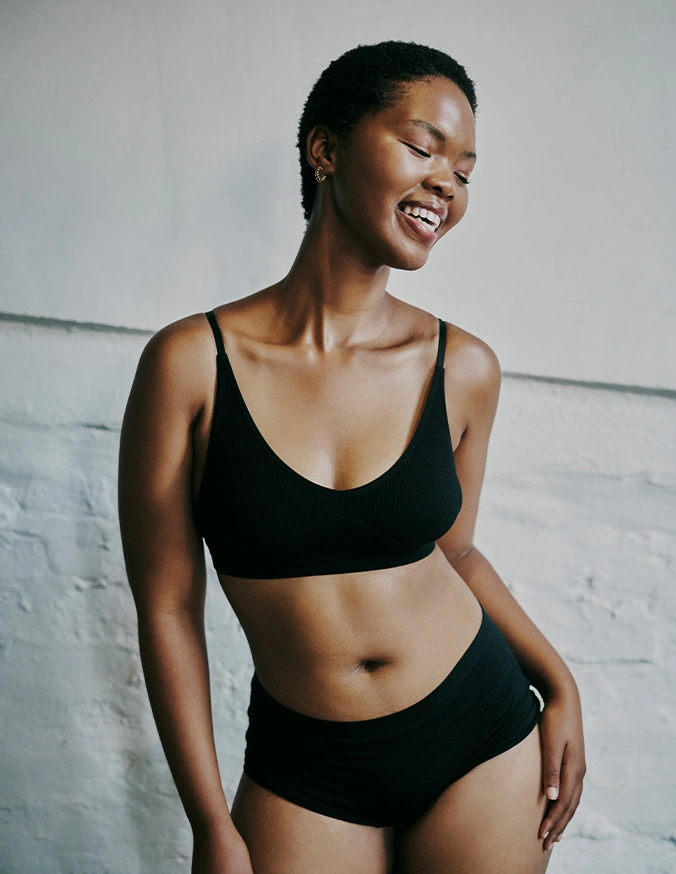 Woman smiling in black underwear set showing natural body confidence and comfortable fit - Skin excisions in Brookfield and Appleton, WI.