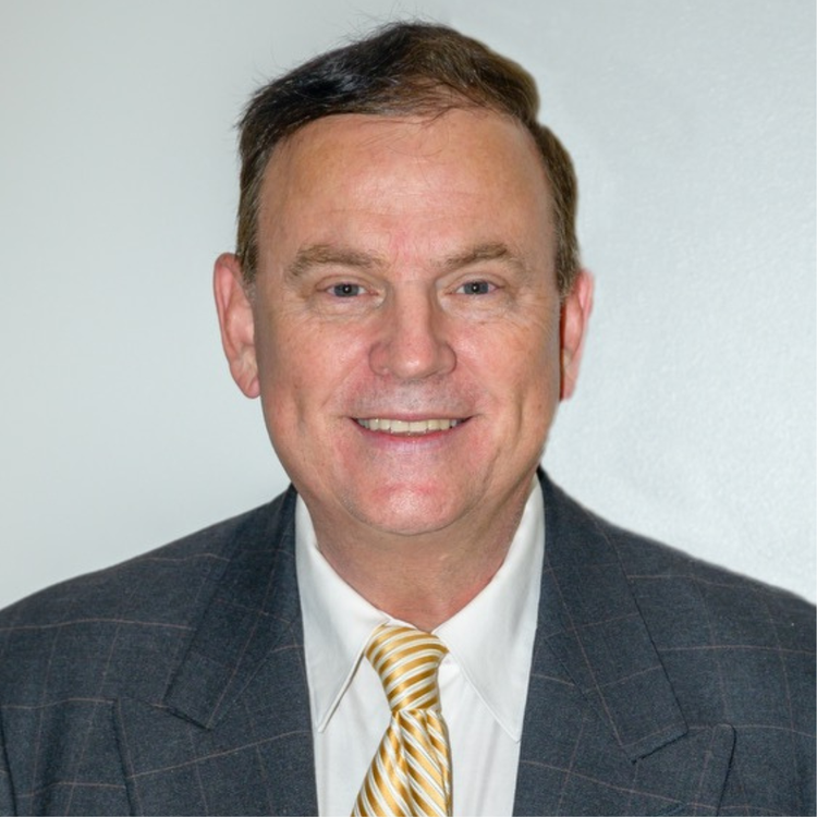 Dr. Philip Conrardy professional headshot in navy suit with striped gold tie smiling at camera