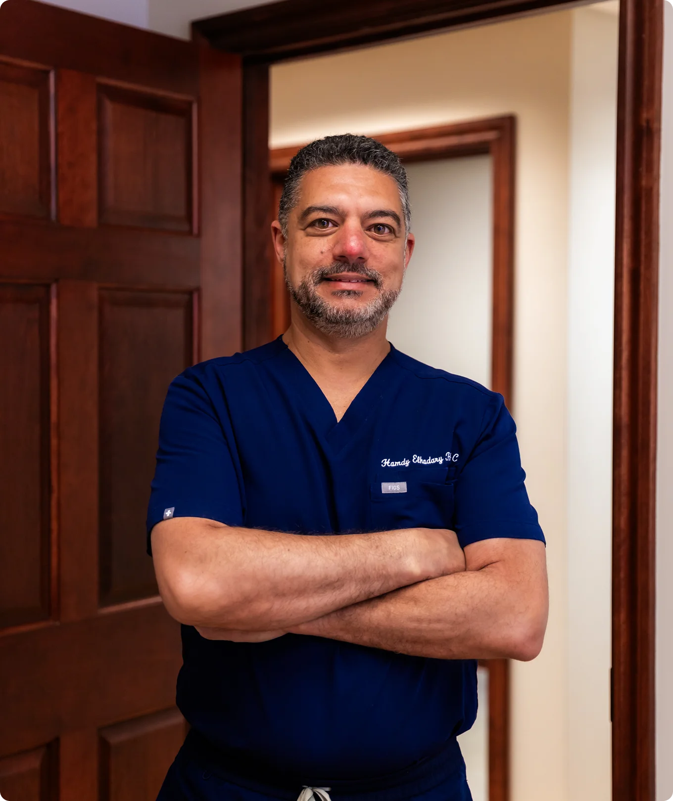Hamdy Elhadary PA-C in navy blue scrubs standing with arms crossed in office doorway - Doctor in Brookfield and Appleton, WI.