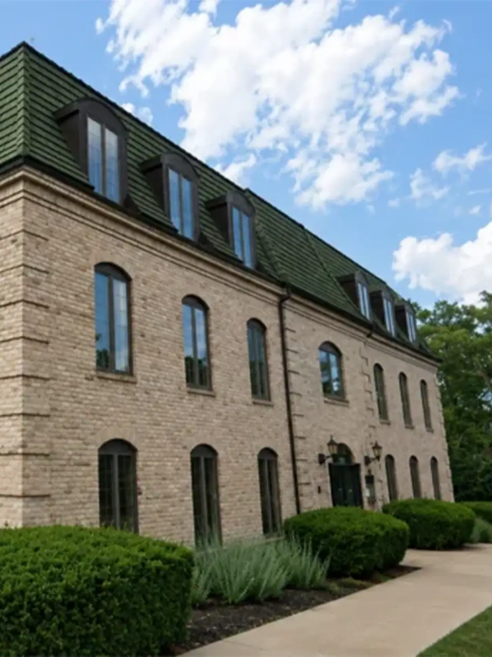 Three-story brick medical office building with green mansard roof and manicured landscaping