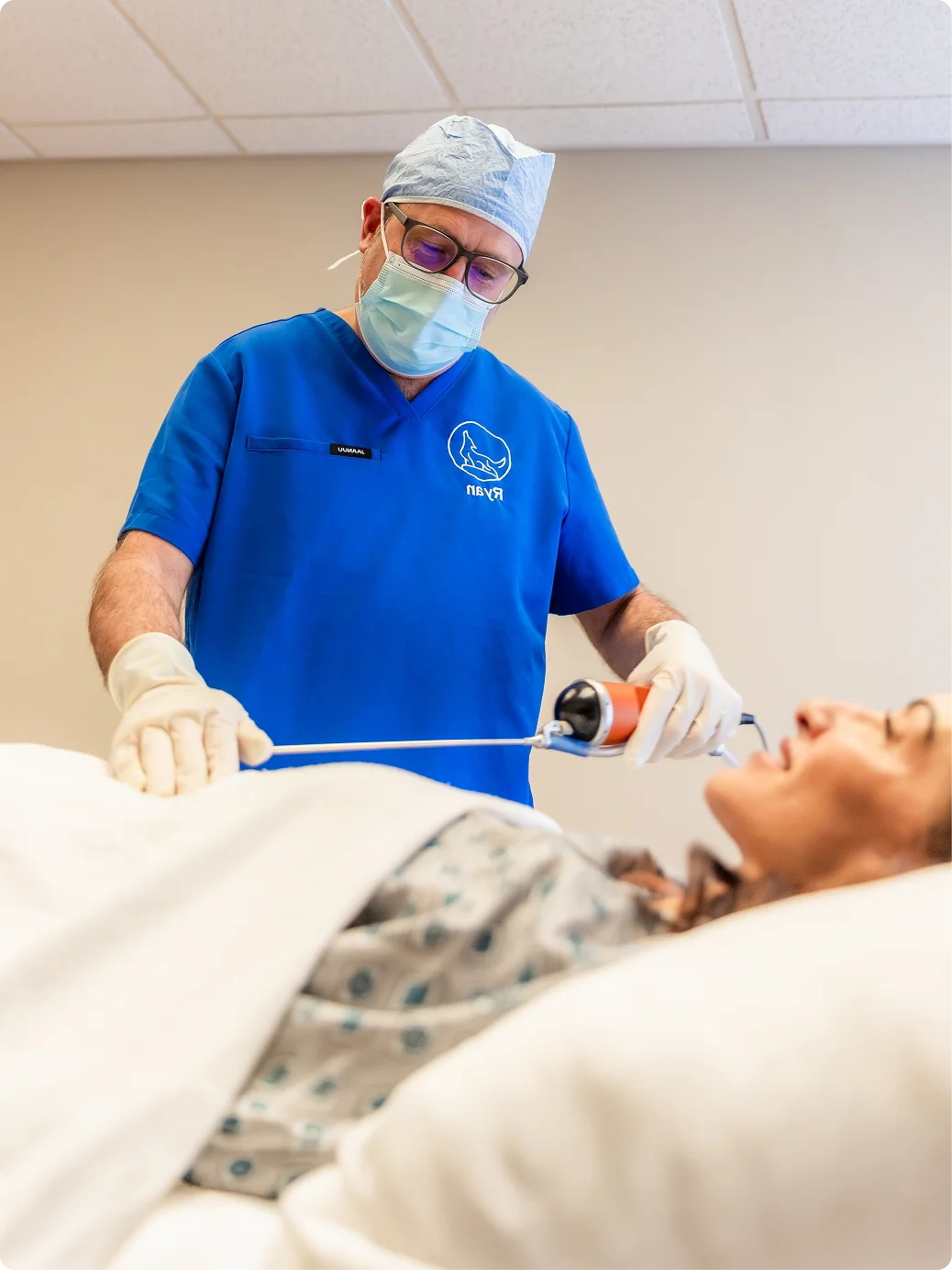 Surgeon in blue scrubs and protective gear performing laser treatment on patient in medical clinic - in Brookfield and Appleton, WI.