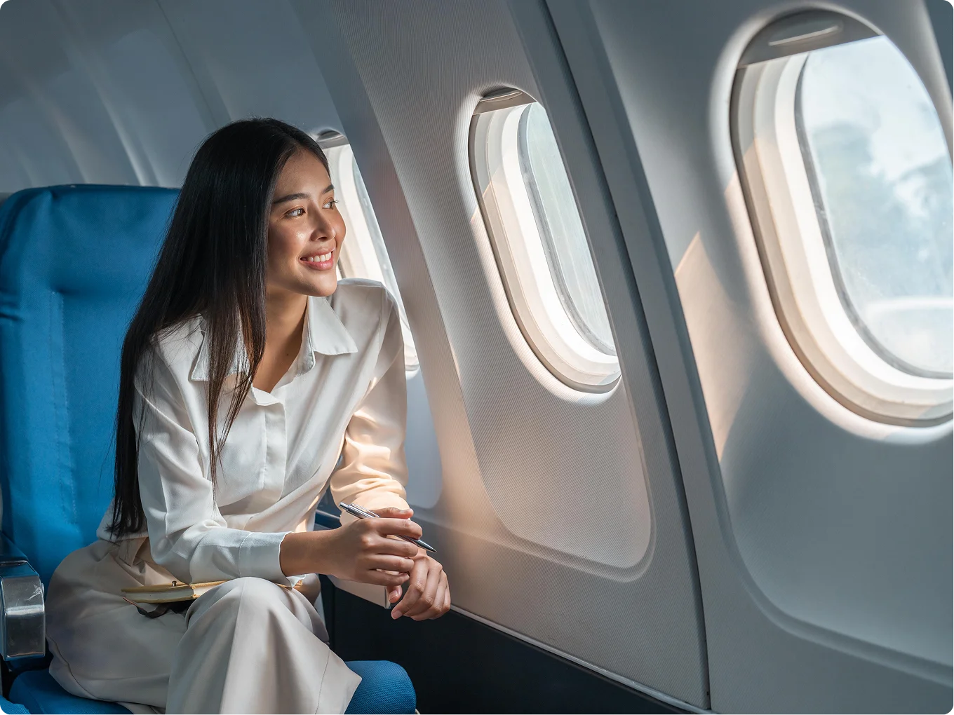 Woman in white shirt enjoying coffee while sitting in airplane seat by window during flight - Resource in Brookfield and Appleton, WI.