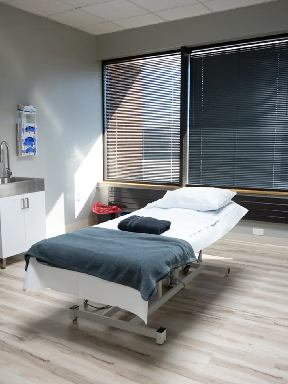 Modern medical examination room with treatment table, large windows, and clean minimalist design - In Appleton, Brookfield, Milwaukee, WI & Gurnee, IL