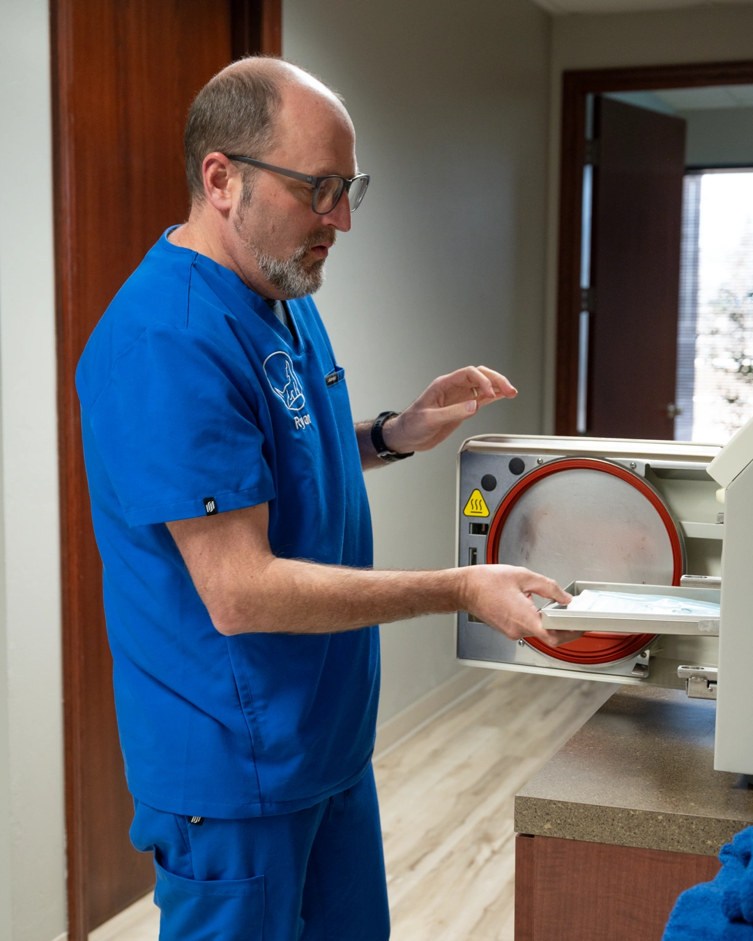 Dr. Conrardy in blue shirt loading tray into white machine in modern medical office - In Appleton, Brookfield, Milwaukee, WI & Gurnee, IL
