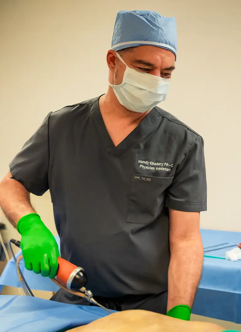 Hamdy Elhadary PA-C in scrubs and surgical mask examining patient during dad bod makeover consultation - Dad bod In Appleton, Brookfield, Milwaukee, WI & Gurnee, IL