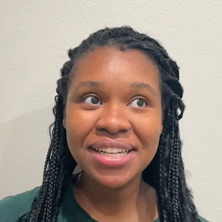 Young woman with braided hair smiling at camera, sharing her healthcare experience and patient journey