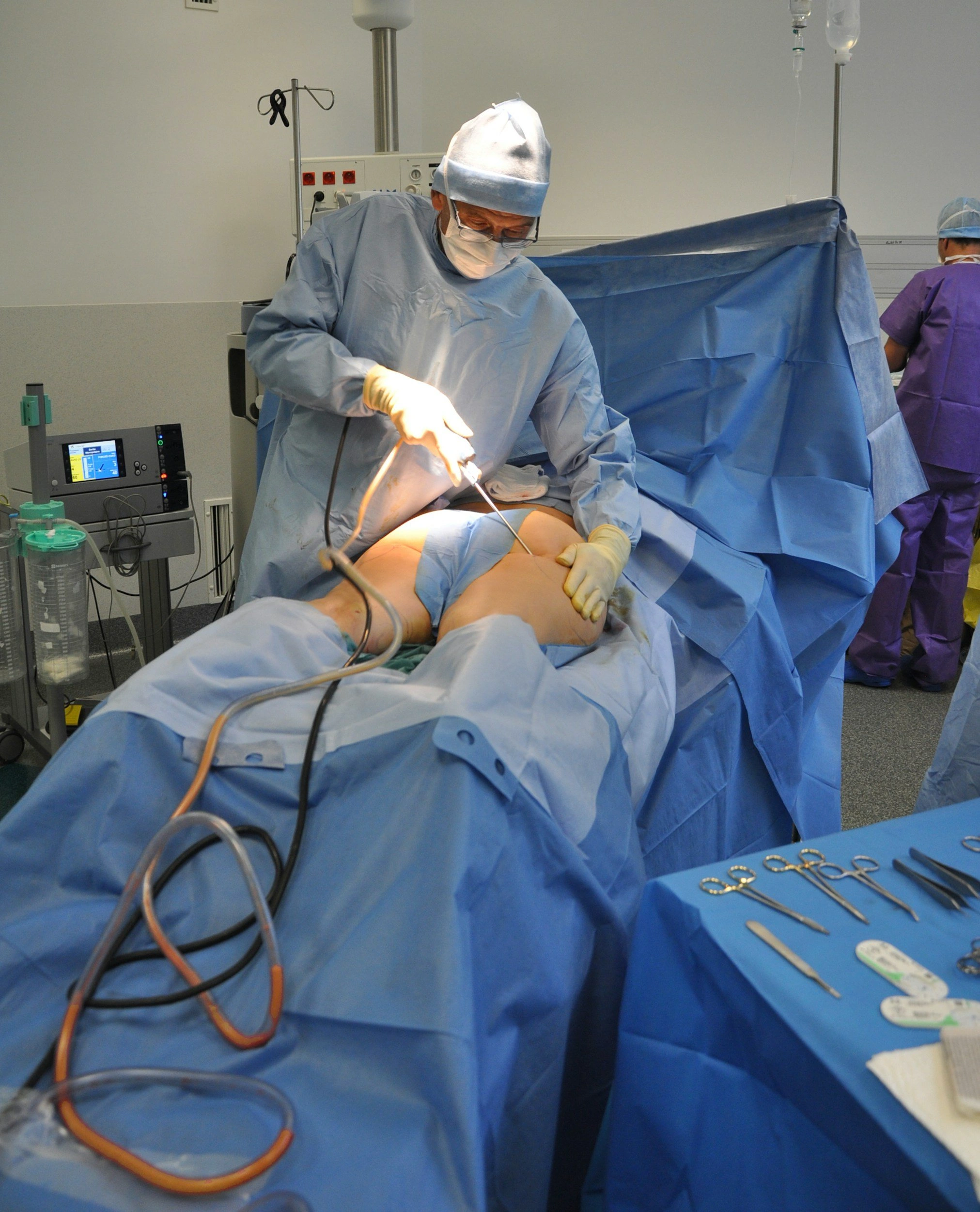 Dr. Conrardy performing knee arthroscopy procedure in operating room with sterile blue drapes and medical equipment - In Appleton, Brookfield, Milwaukee, WI & Gurnee, IL