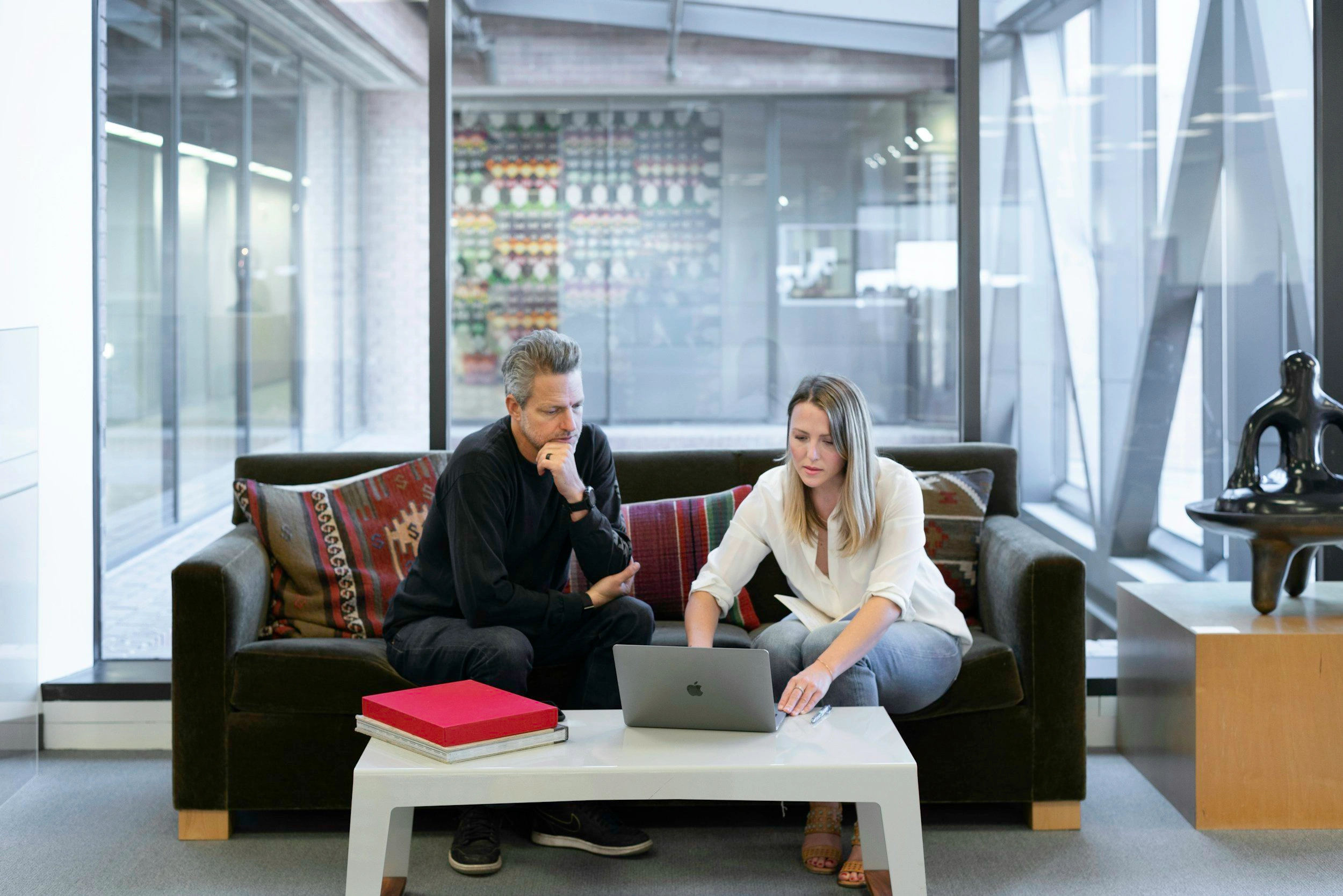 Two professionals having a business meeting on modern office sofa in contemporary workspace with glass walls - In Appleton, Brookfield, Milwaukee, WI & Gurnee, IL